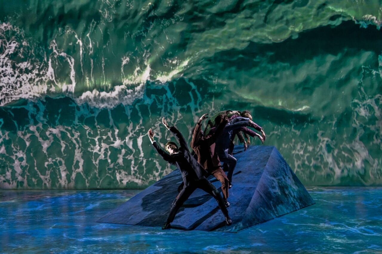 A group of dancers from Mod Ballet performs on a sloped platform, with a large projection of ocean waves as the background—a scene reminiscent of Quadrophenia’s seaside atmosphere.