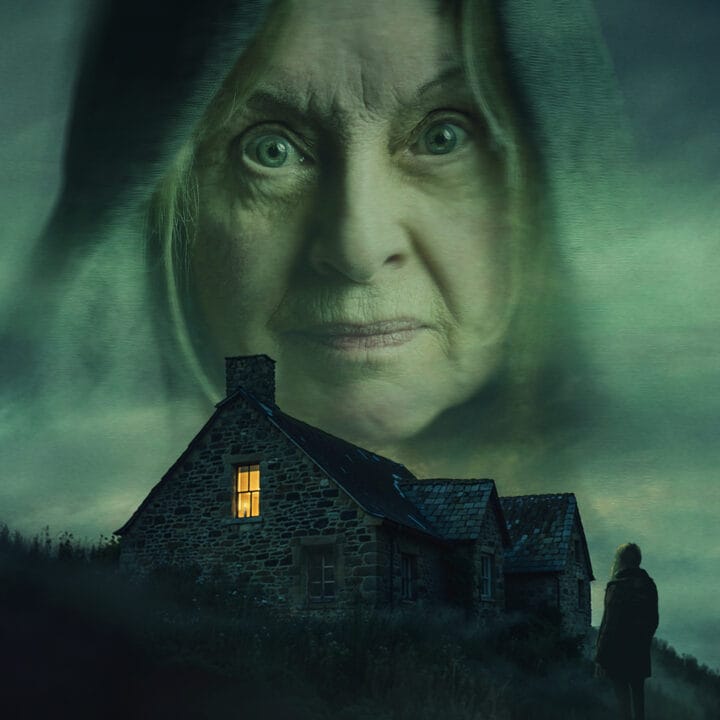 A stone house with one lit window sits under a dark, cloudy sky. A large, transparent face of an older woman looms above, while a lone figure stands outside.