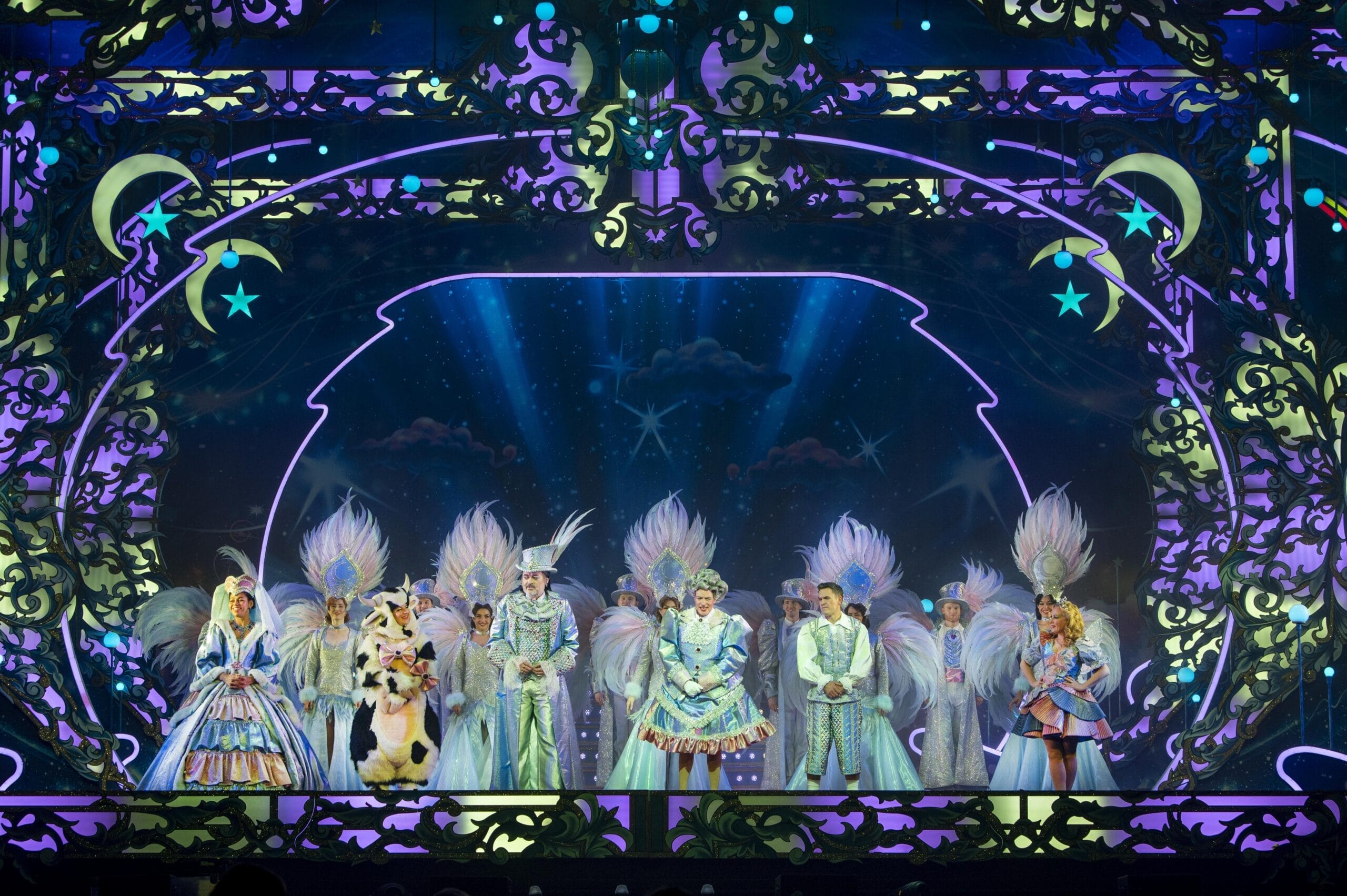 Performers in elaborate, colorful costumes bring Jack and the Beanstalk to life on a brightly lit stage, adorned with ornate decorations and a starry night backdrop.
