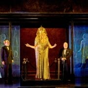 Five people stand on stage in formal and period costumes, with one person dressed as an Egyptian pharaoh in gold at the center, surrounded by an ancient Egyptian-themed set inspired by Death on the Nile.