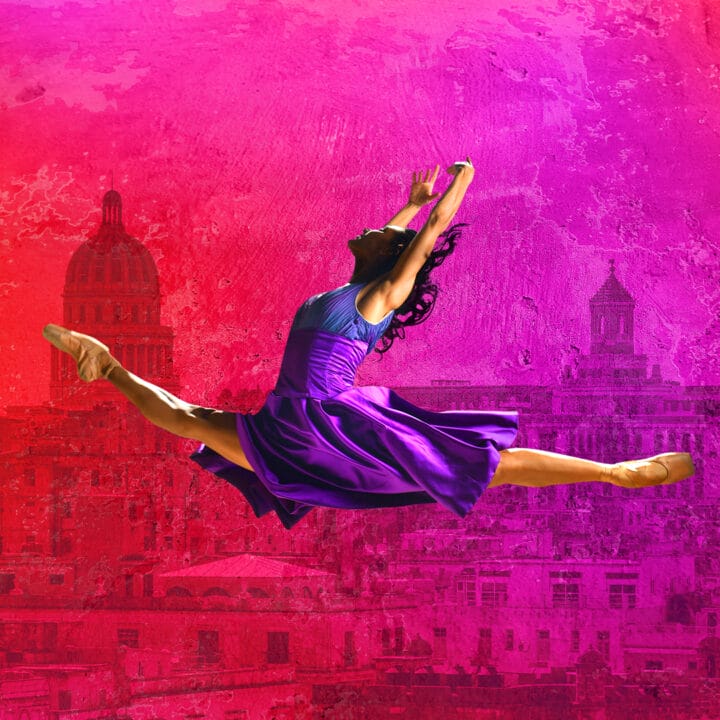 A dancer in a purple dress performs a split leap against a vibrant pink and red background with city buildings and domes.
