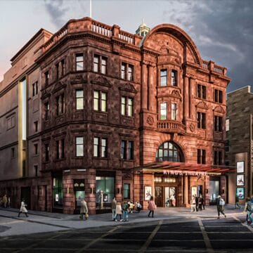 A large red-brick theatre building stands on a street corner, with pedestrians walking nearby and signage reading "KING'S THEATRE" above the entrance.