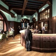People sit and stand around a curved wooden bar inside a stylish café with large windows, wooden floors, and green chairs, during daylight.