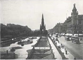 Black and white photo of a busy Princes Street with trams, pedestrians, and The Scott Monument at the center.