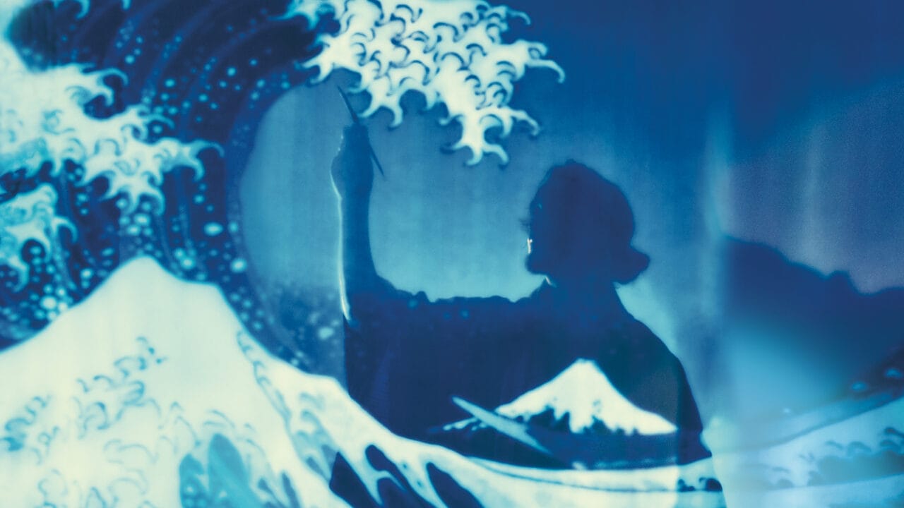 A person’s silhouette holding a brush appears against a background resembling Hokusai's Great Wave, with stylized waves and Mt. Fuji visible.