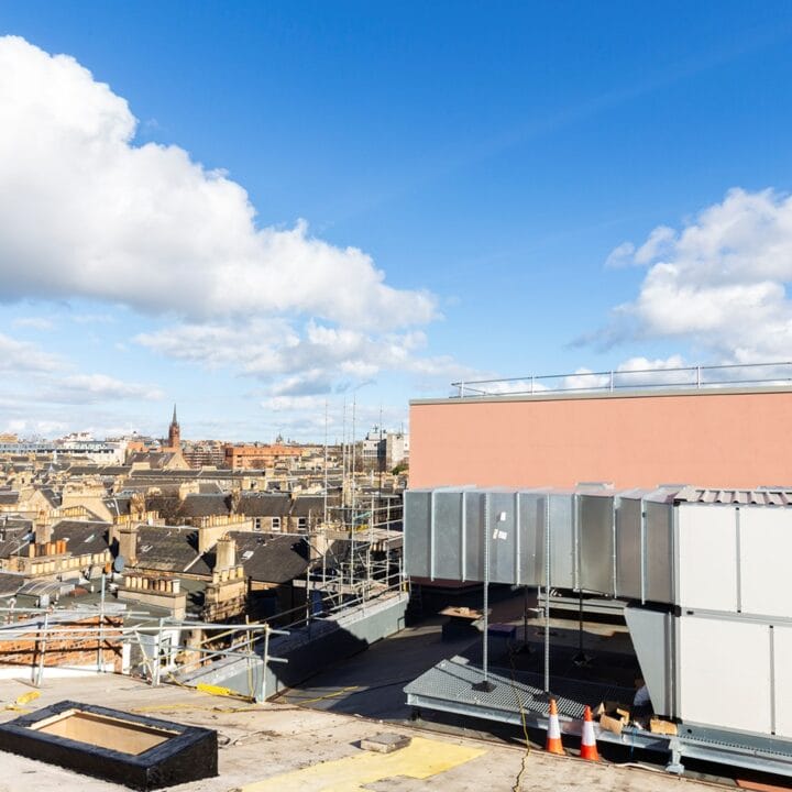 Rooftop view of a city, scaffolding, and Edinburgh Castle in the background.