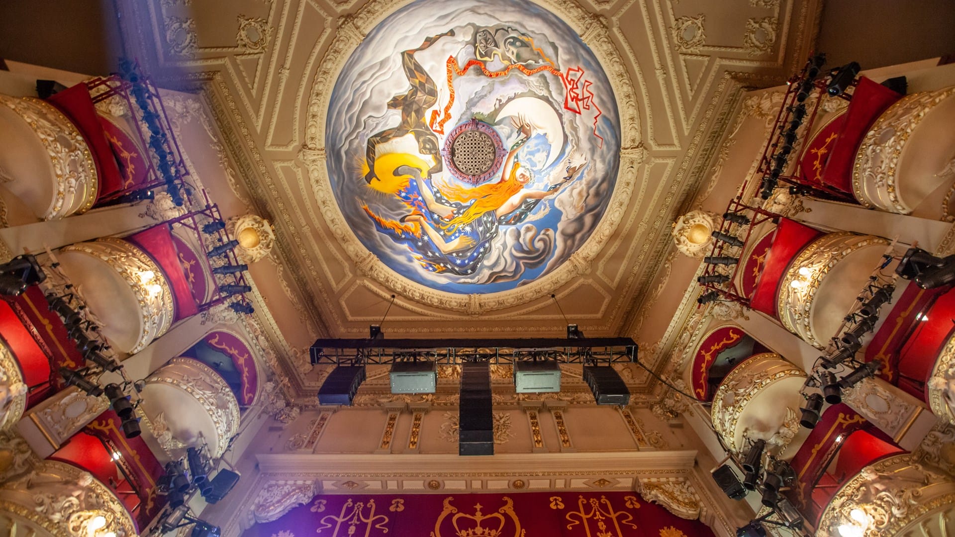 View of the King's Theatre ornate ceiling with a colourful circular mural, surrounded by gold decorative elements and red velvet balcony seats.