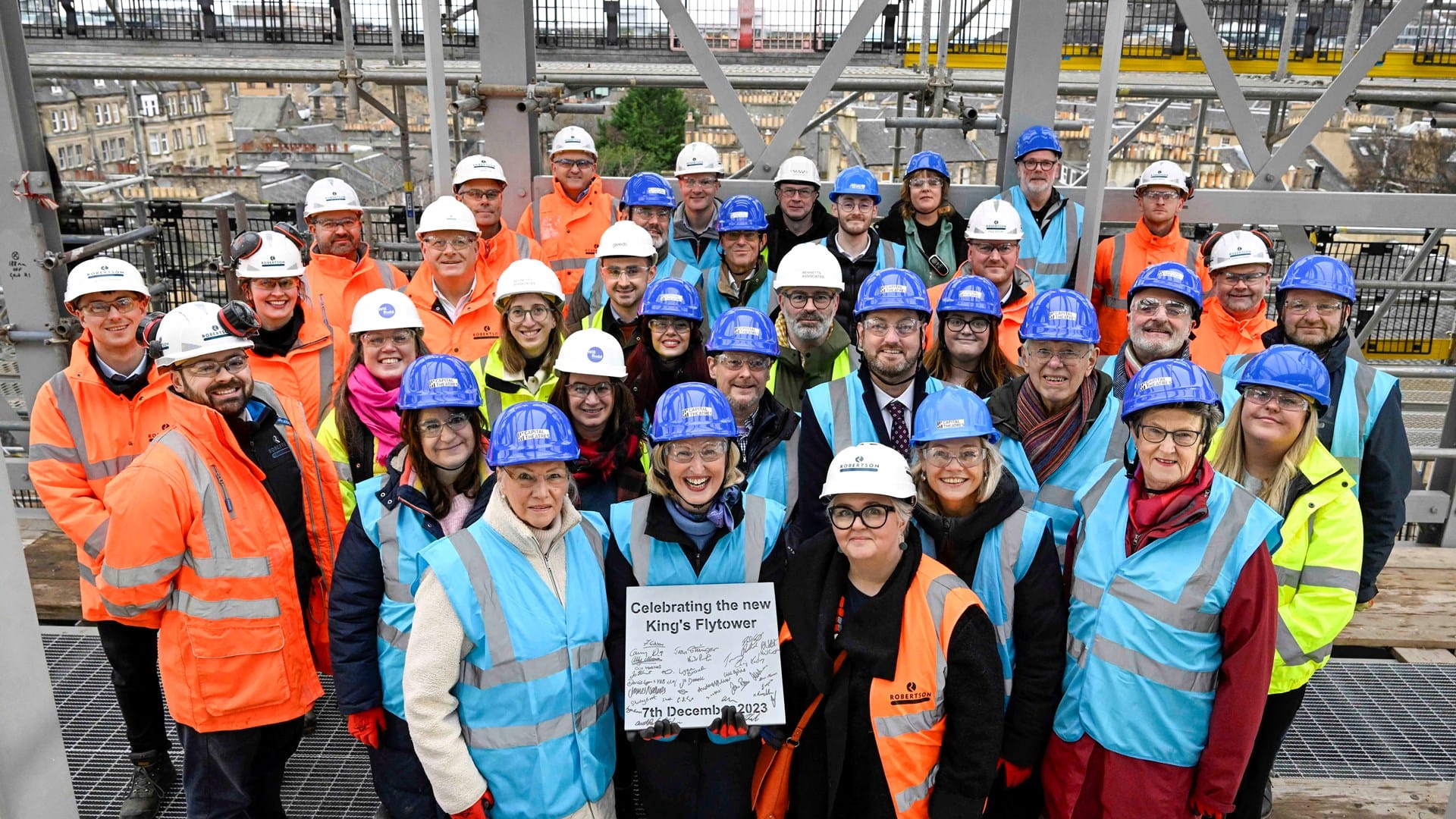 A group of people wearing hard hats and high-visibility vests pose on a construction site, holding a sign that reads "Celebrating the new King's Flyover, 15th December 2023.