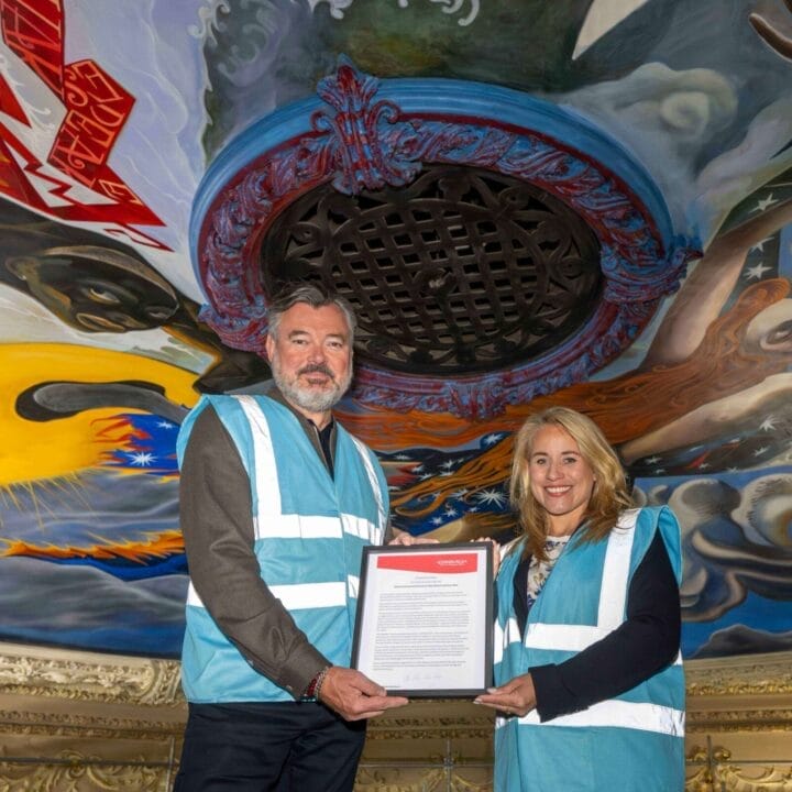 Grant Stott and Councillor Munro hold a framed document while standing under the King's Theatre ceiling mural.