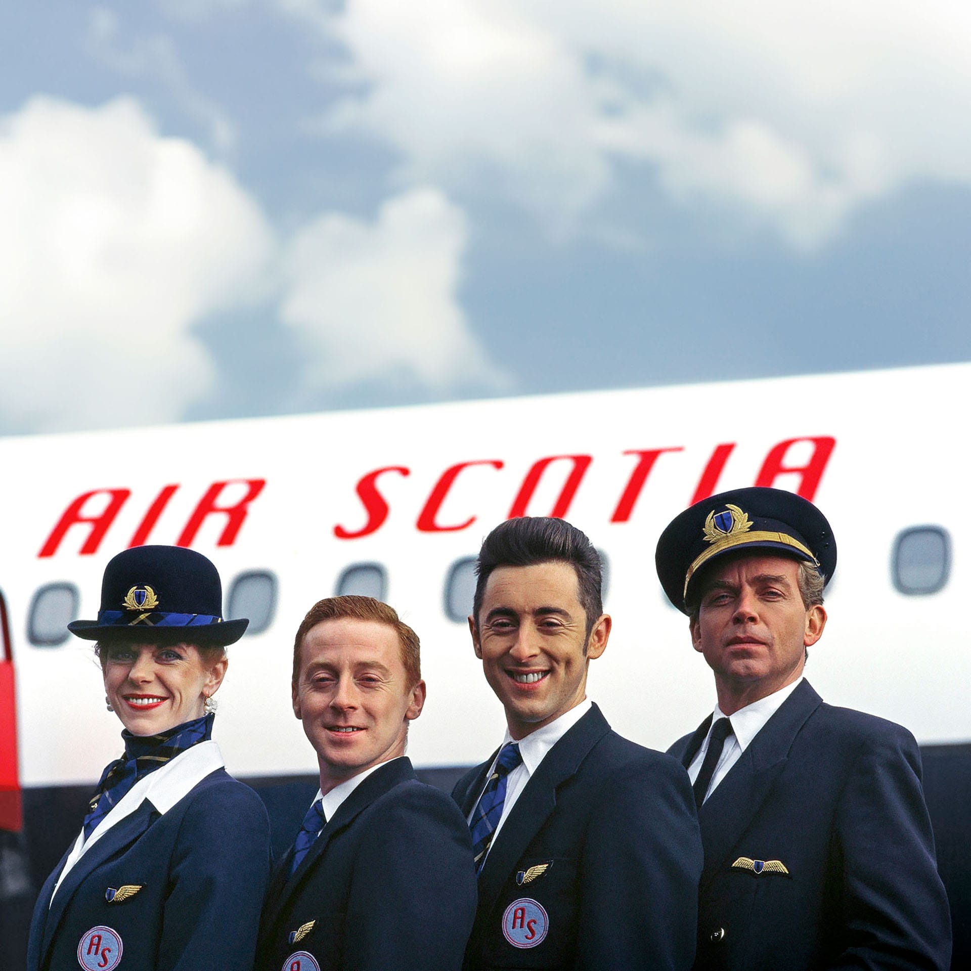 Four airline crew members in uniform stand in front of an airplane with "Air Scotia" written on it, posing for a group photo and embodying the High Life of aviation.
