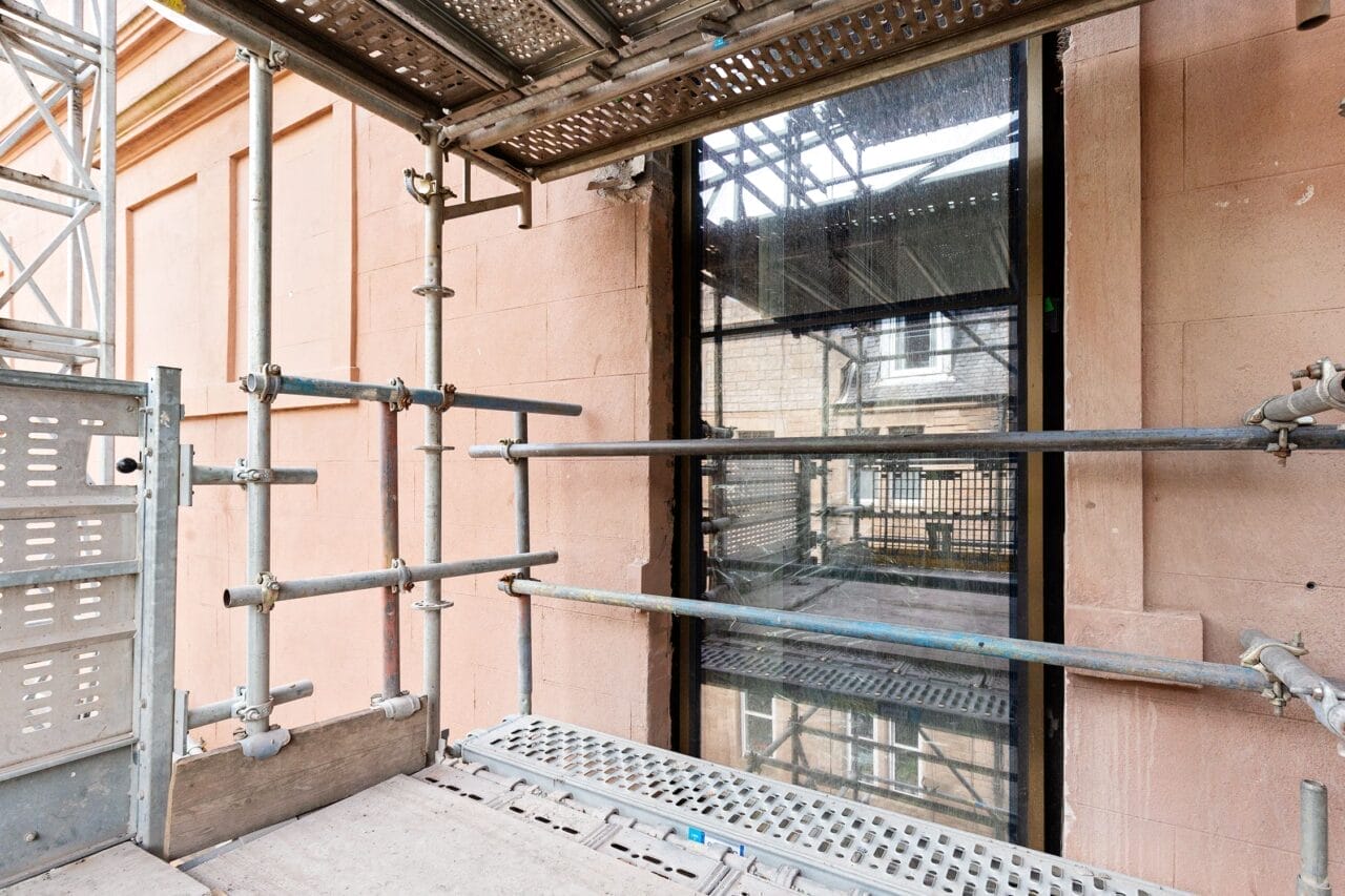 Scaffolding set up outside a stone building showcasing the new slot window on the exterior of the King's building.