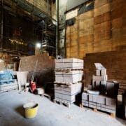 Stacks of concrete blocks and construction materials are arranged on pallets, in preparation for construction of the stage basement and stage floor in the King's Theatre.