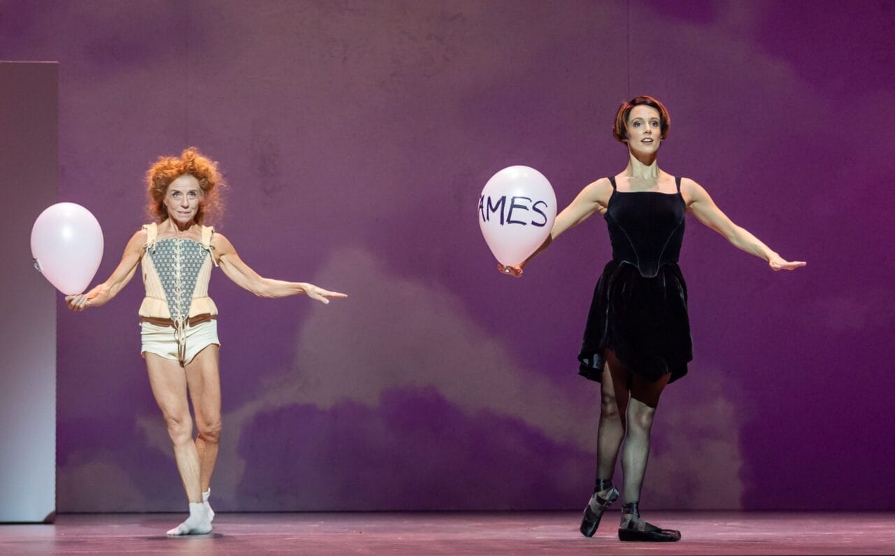 Two ballet dancers perform on stage, each holding a white balloon—one bearing the name Mary Queen of Scots. The purple backdrop highlights this elegant nod to the legendary Scottish monarch.