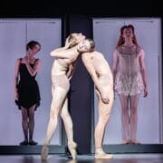 Four ballet dancers perform on stage, two posing back-to-back in the foreground, while two others evoke regal poise in separate doorways—a scene reminiscent of Mary, Queen of Scots’ elegant court.
