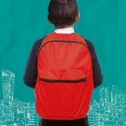 A child with a red backpack stands facing a teal background with white illustrated city buildings and skyscrapers, evoking the spirit of Onjali Q. Raúf's beloved children's book, The Boy at the Back of the Class.