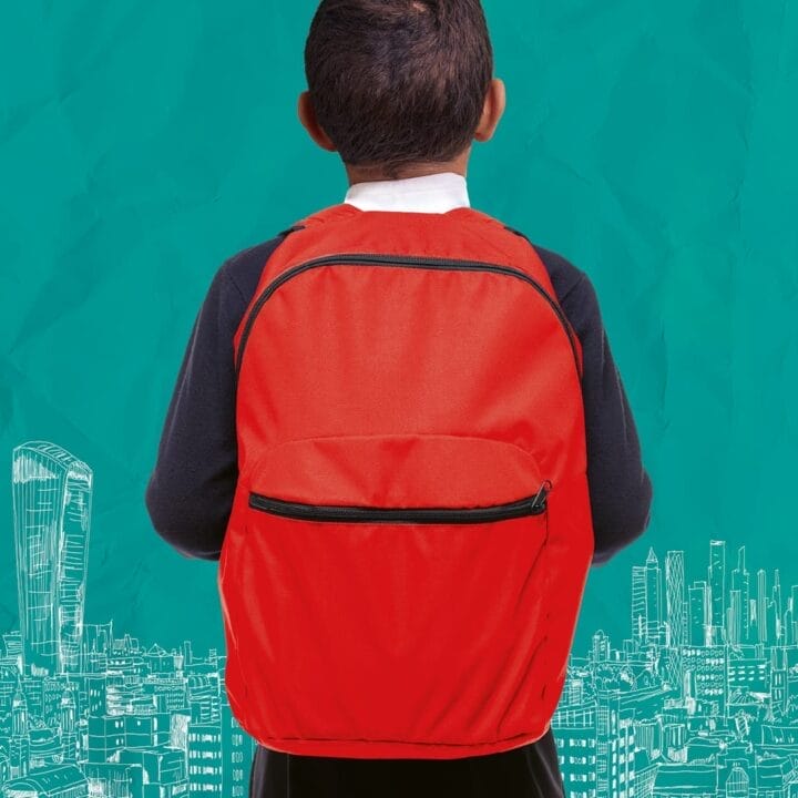 A child with a red backpack stands facing a teal background with white illustrated city buildings and skyscrapers, evoking the spirit of Onjali Q. Raúf's beloved children's book, The Boy at the Back of the Class.