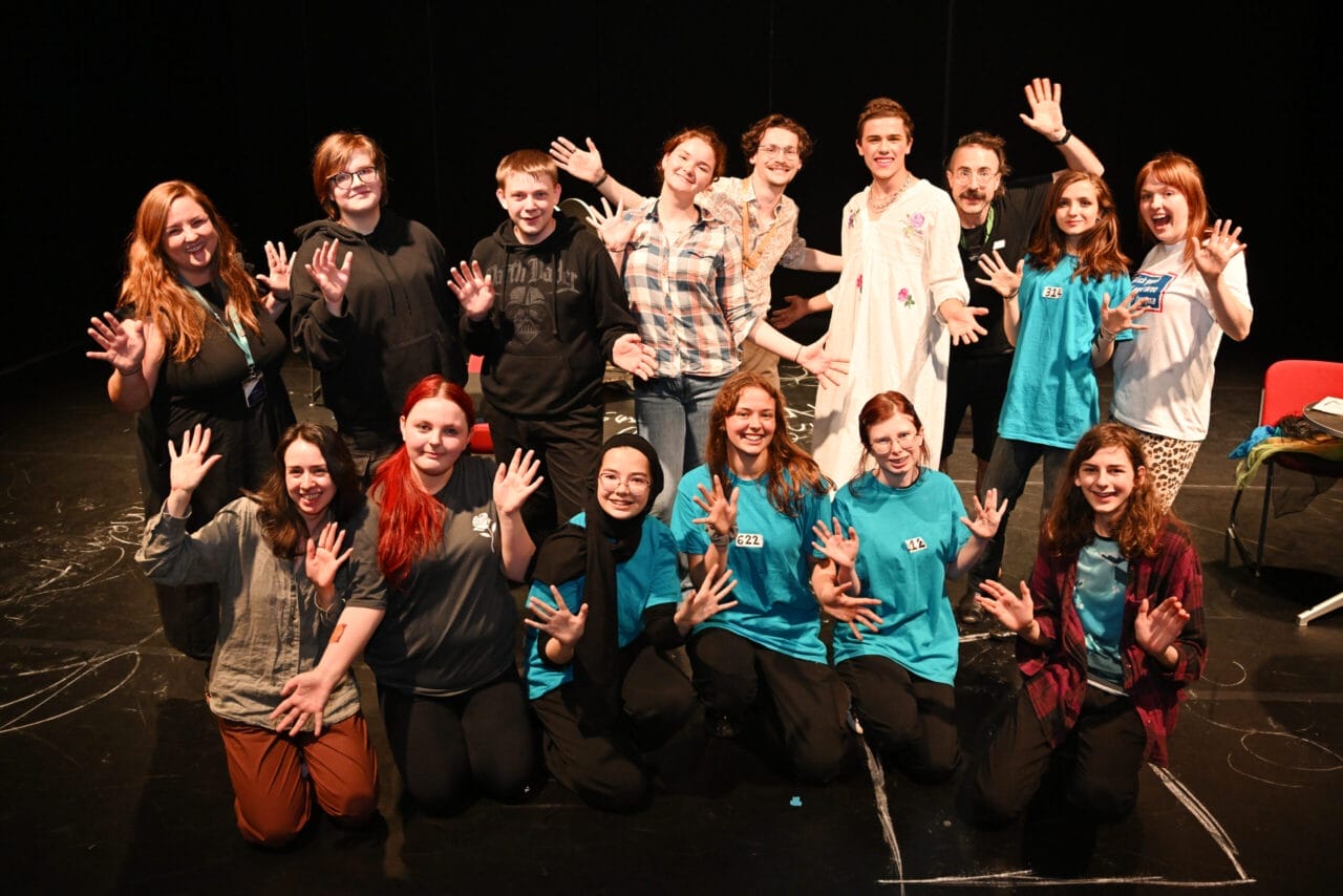 A group of young people smiling and posing with jazz hands.