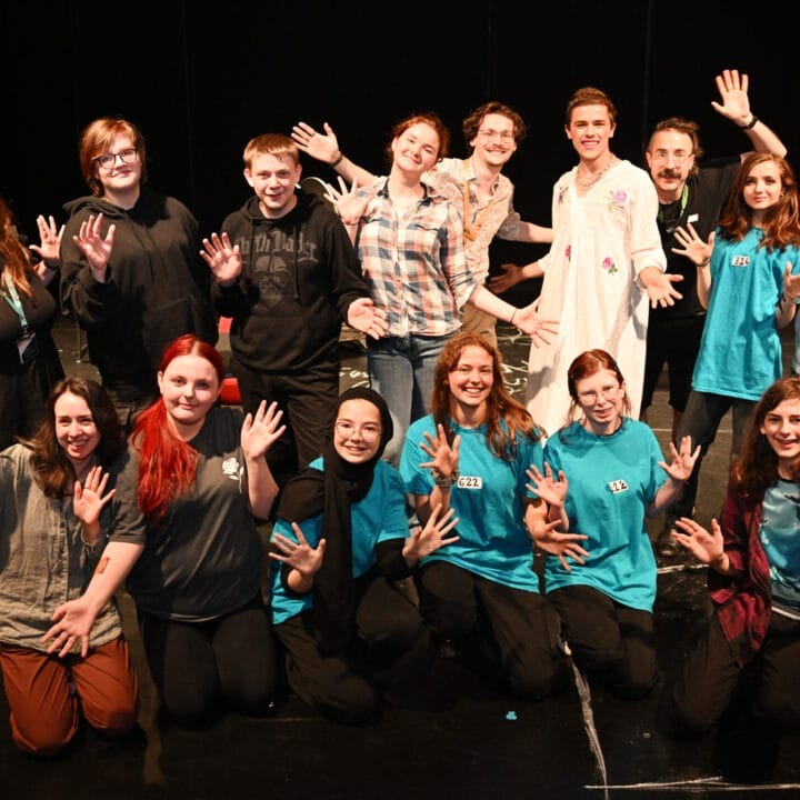 A group of young people smiling and posing with jazz hands.