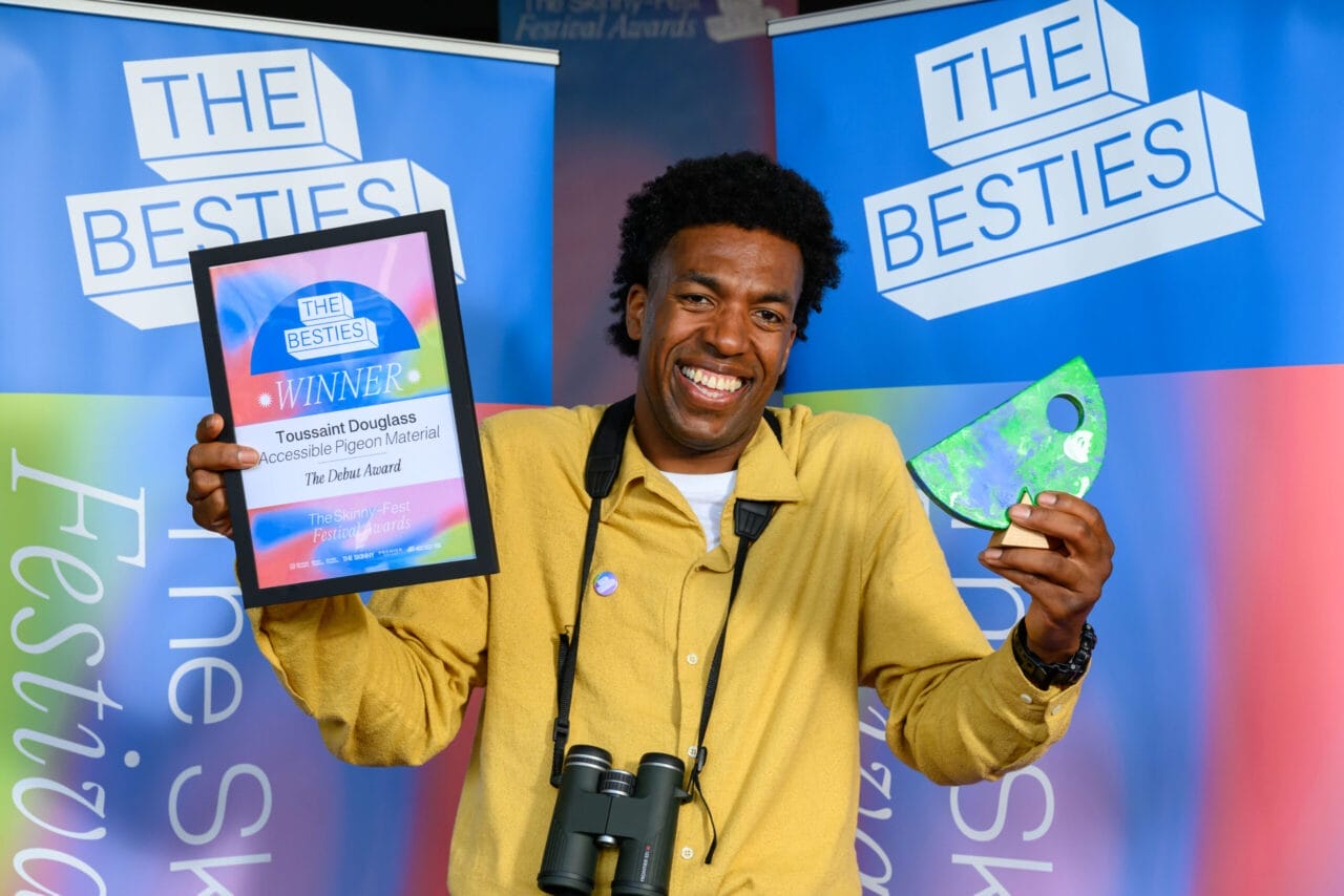 A man holding up two awards, celebrating as one of the first winners of the 2025 Besties.