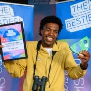 A man holding up two awards, celebrating as one of the first winners of the 2025 Besties.