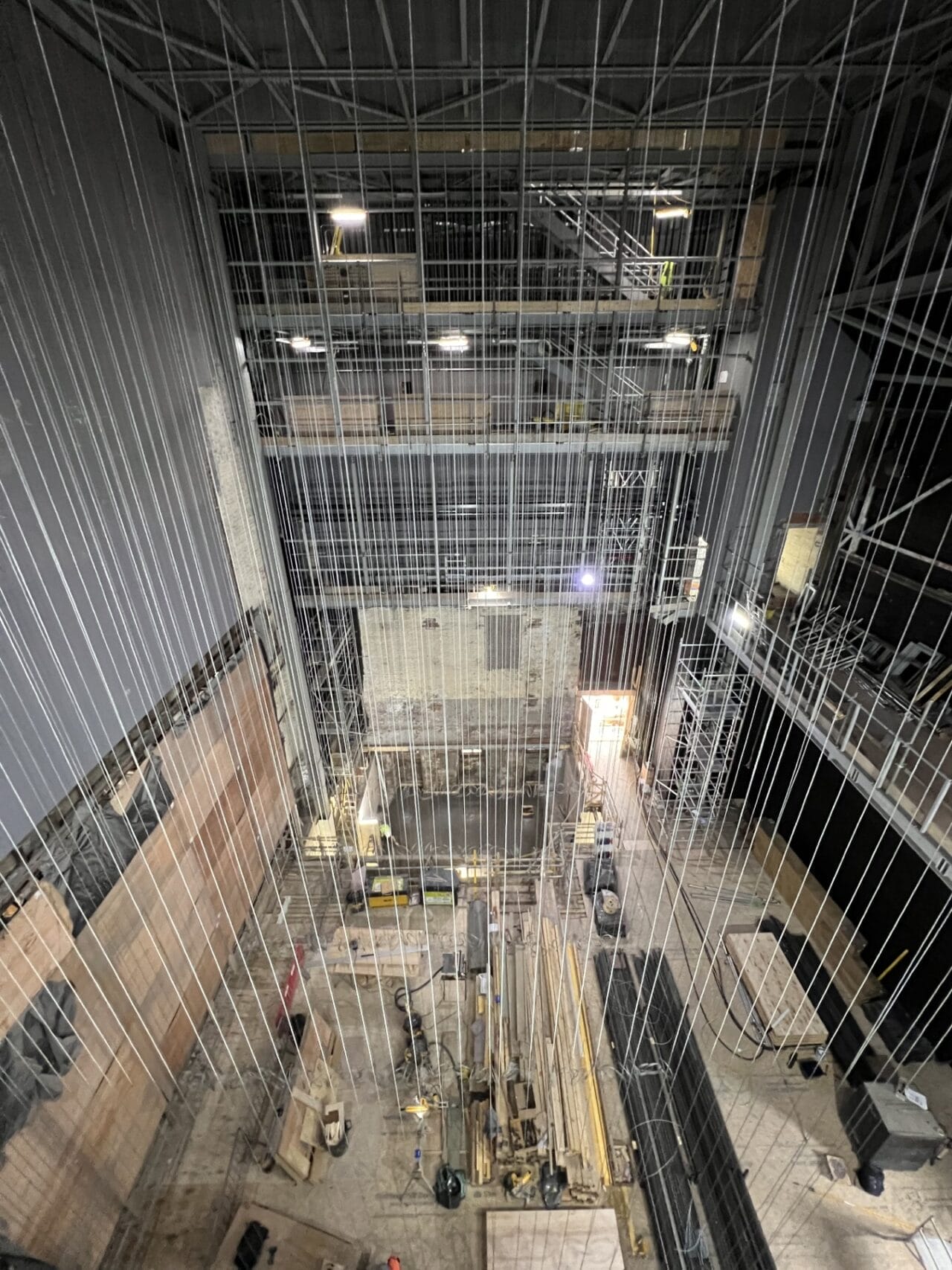 View from above of the King's Theatre Redevelopment, showing a multi-story industrial construction site with scaffolding, cables, wooden boards, and equipment scattered across the floor.