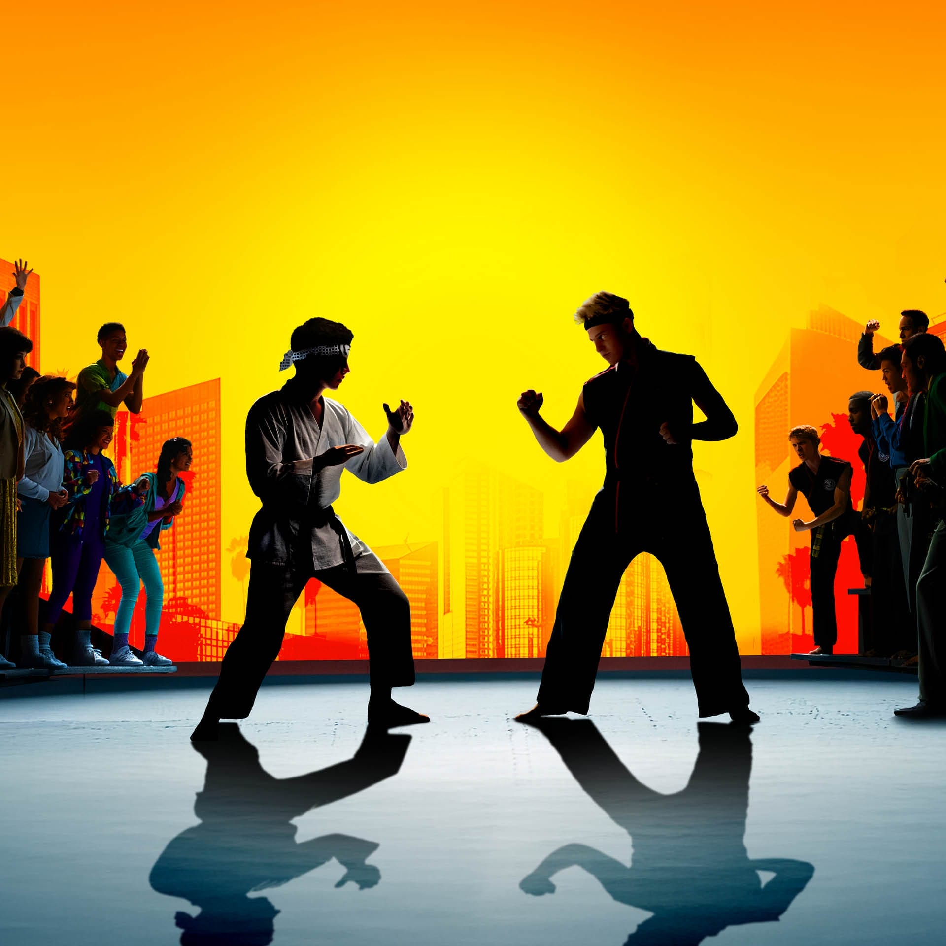 Two people in martial arts stances face each other, as a crowd watches against a bright yellow and orange city skyline.