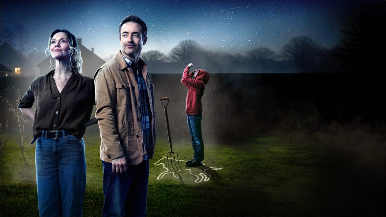 A woman and a man stand in the foreground of a garden at night; in the background, evoking The Curious Incident of the Dog in the Night-Time, a child looks up at the sky near a spade and an animal outline drawn on the ground. Trees and houses sit further off.
