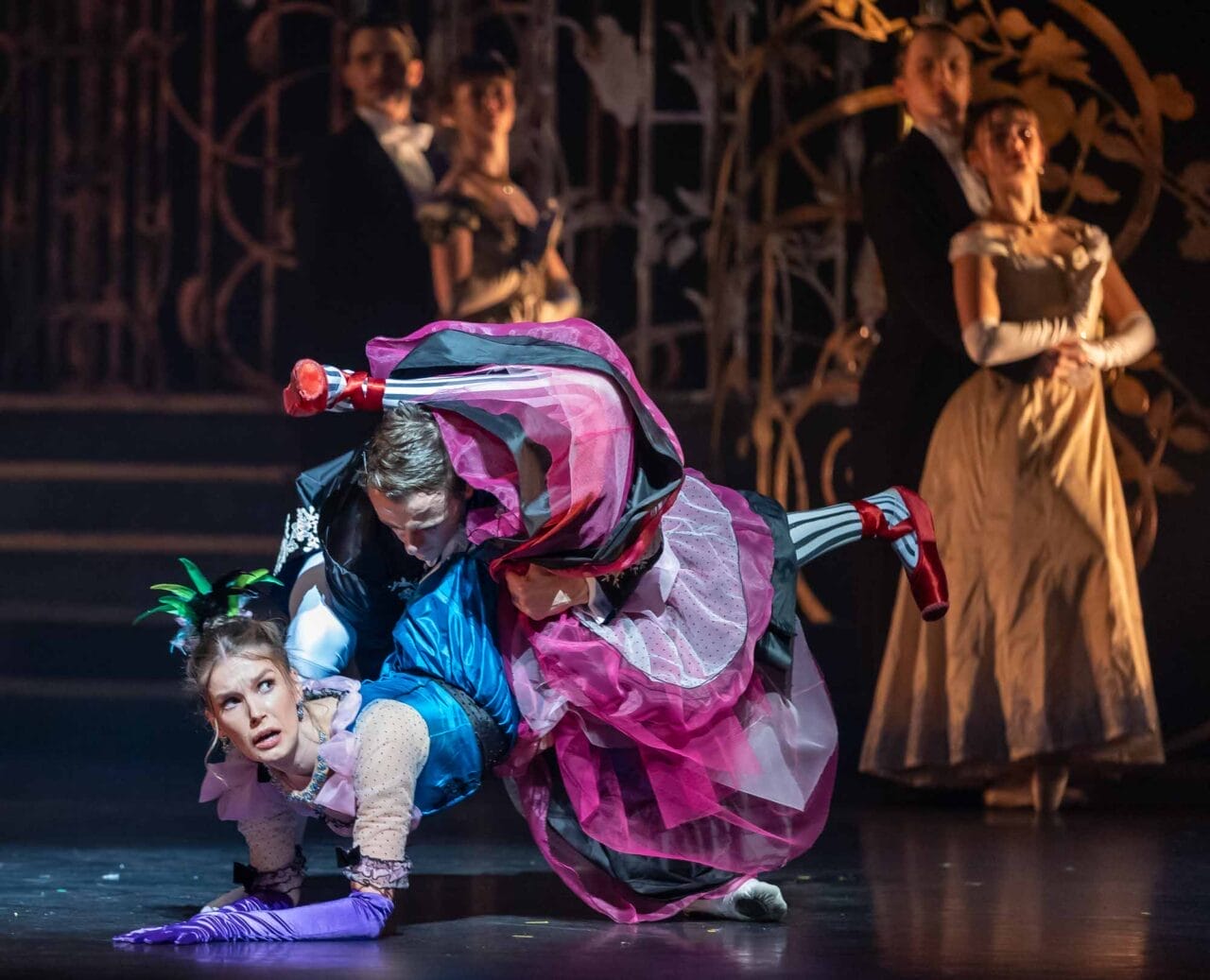 A theatrical dance scene with a man dramatically dipping a woman in a colourful dress and striped stockings.
