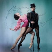 Two ballet dancers pose against a teal background. One, dressed in pink, bends backwards gracefully, while the other channels Gentleman Jack in black attire with a top hat and cane. Artistic symbols and swirls surround them.