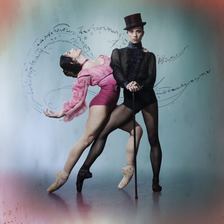 Two ballet dancers pose against a blue backdrop. One, in pink, leans back en pointe with arms outstretched, while the other channels Gentleman Jack in black attire with a top hat and cane. Swirling text-like graphics appear behind them.